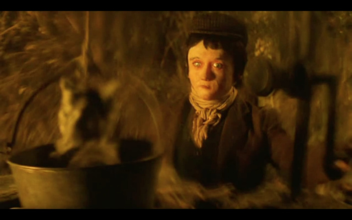 Image: A boy stares at a cat in a well bucket. The boy has eerily blank features.