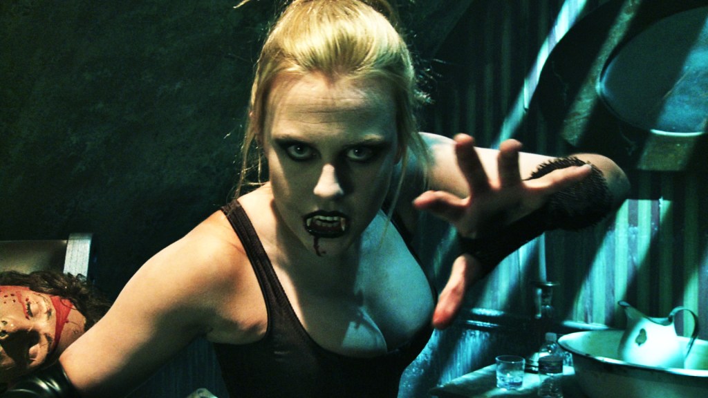 A still from Scare Zone. A haunt actress wears a low-cut top and menaces the camera with fake fangs and blood dripping down her chin. 