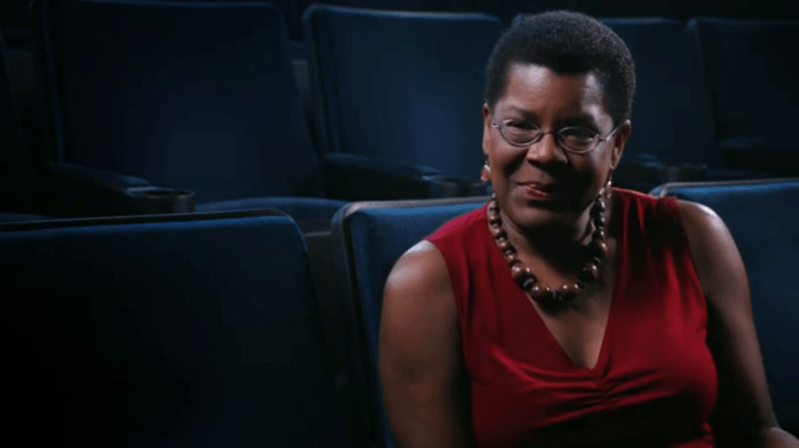 Tananarive Due seated in a movie theatre smiling as she looks at an off-screen interviewer.